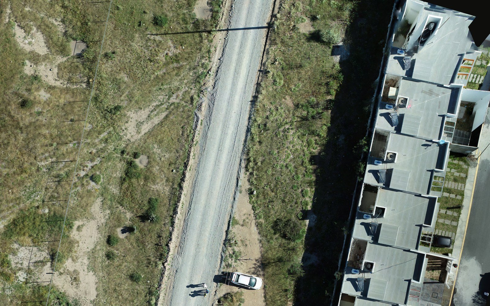 Ortofoto aérea de un levantamiento con dron: camino, terreno natural y vivienda en la orilla del predio