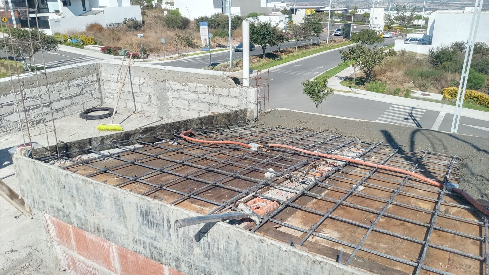 Armado de losa de azotea sobre muro de block, con poliducto eléctrico ya colocado y vista aérea del fraccionamiento y las calles.