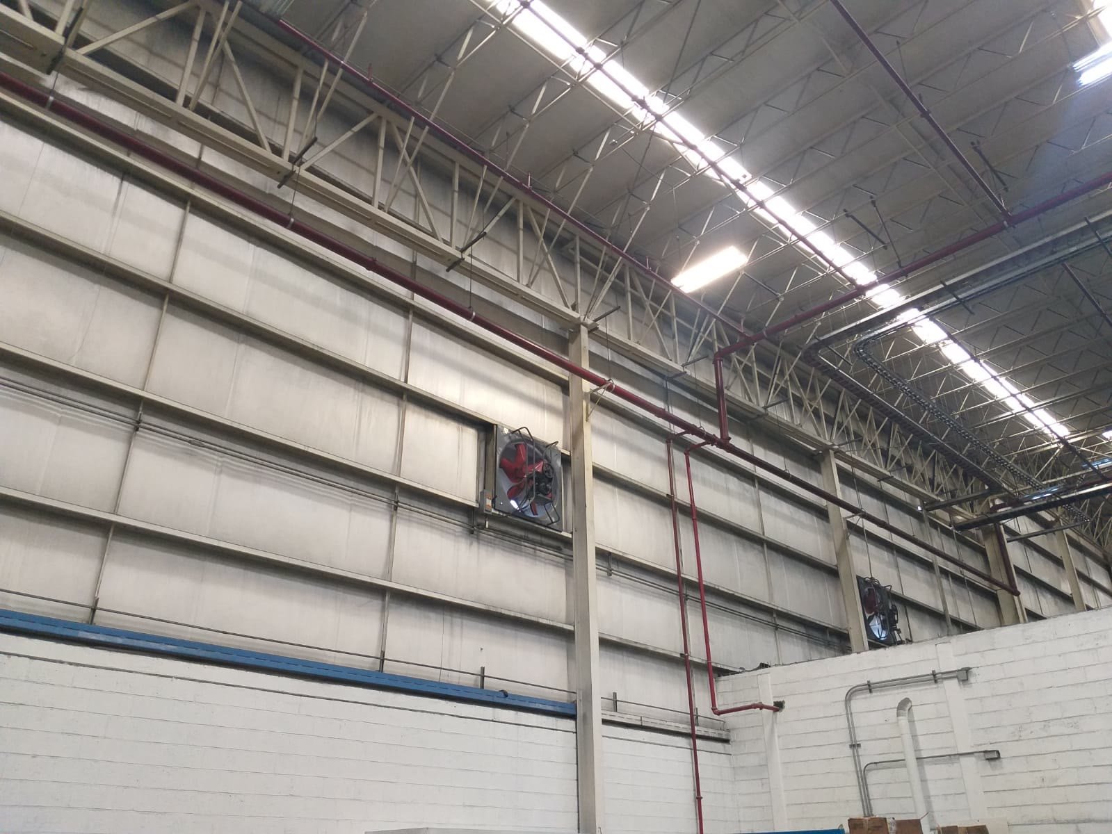 Armadura de acero y red contra incendio en tubería roja bajo la cubierta de una nave industrial