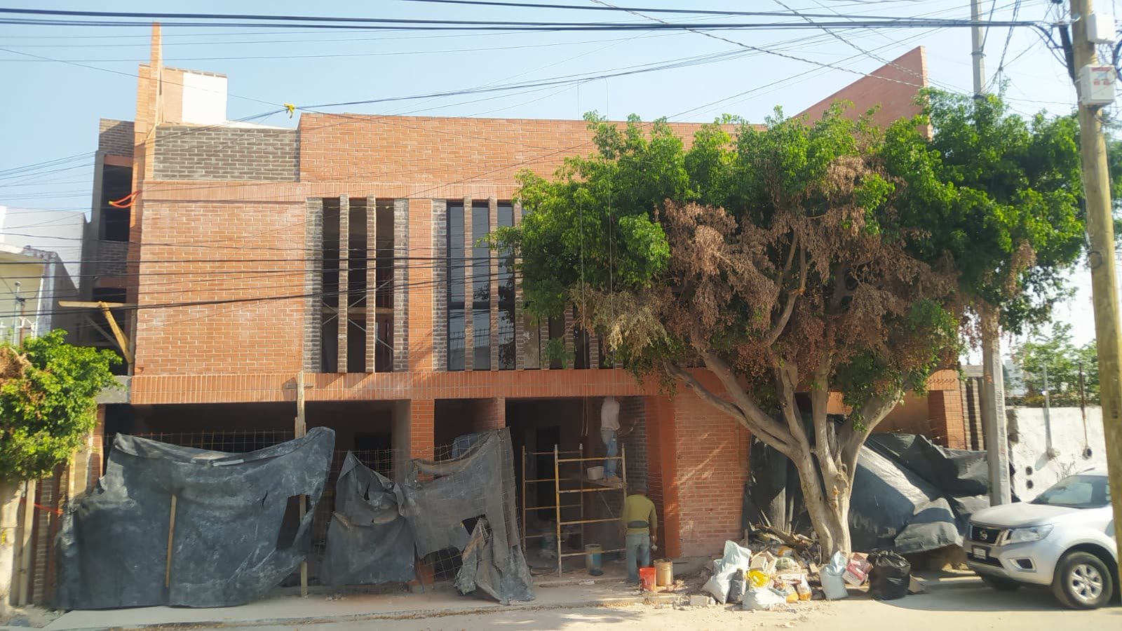 E9 — vista de la fachada de tabique en obra, con el remate del cubo de escalera al fondo