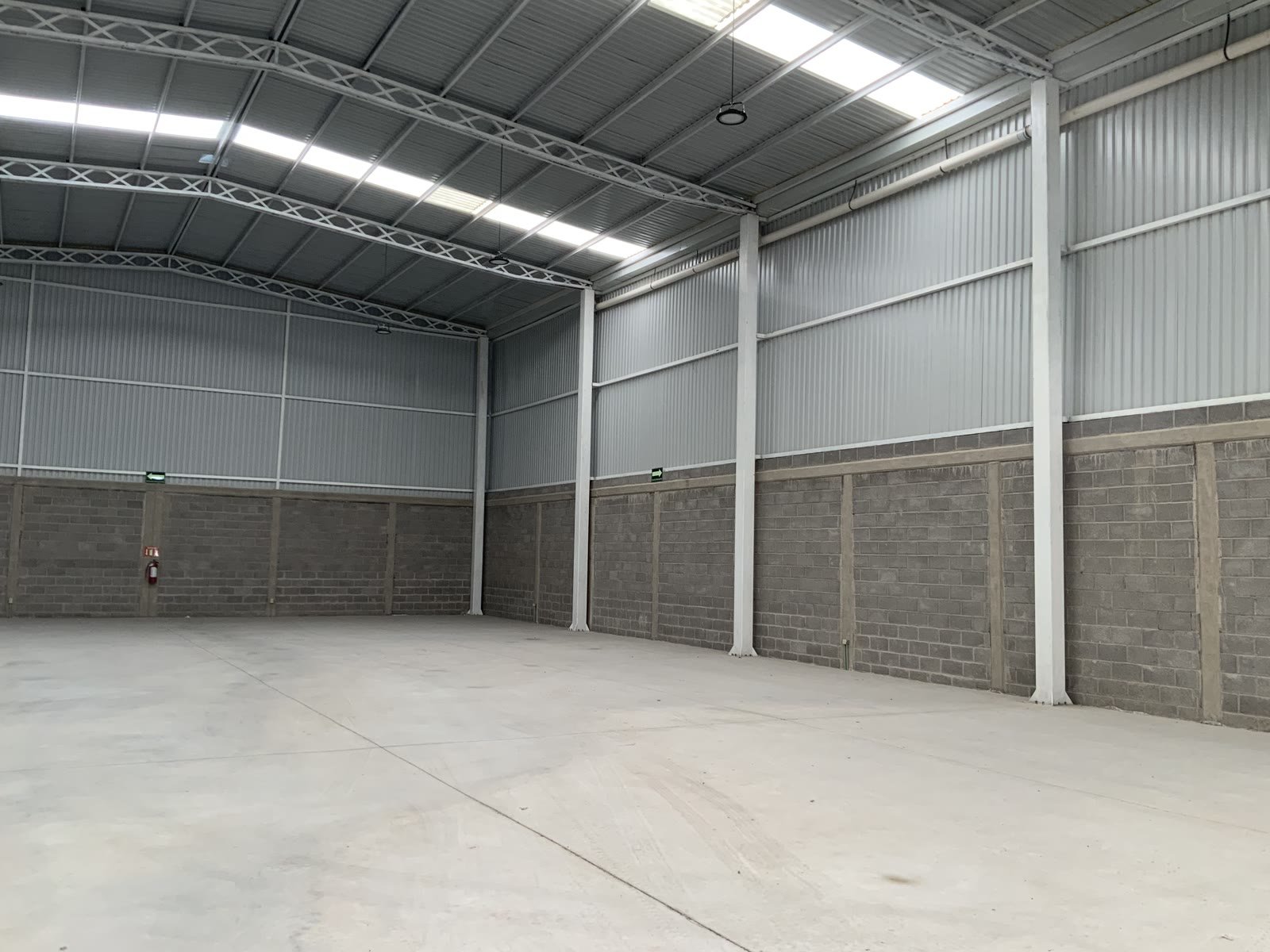 Nave industrial 47-C — esquina interior con columnas de acero, armadura de cubierta y lucernarios, Querétaro
