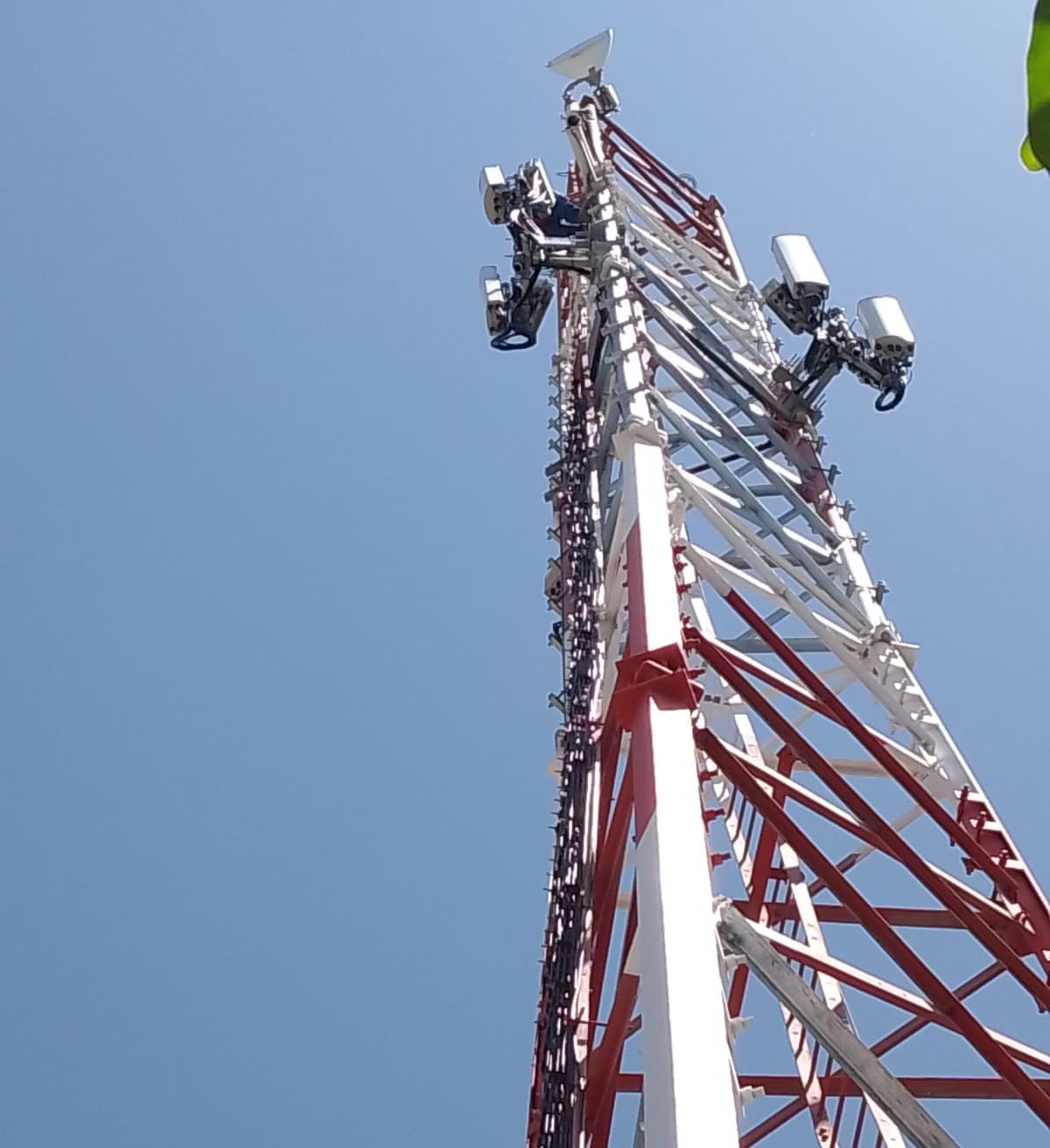 Contrapicado en diagonal de una torre de telecomunicaciones reforzada, con las antenas del remate recortadas contra el cielo