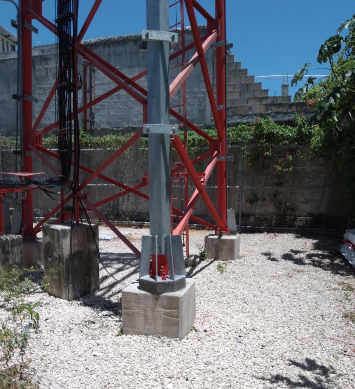 Montante de acero galvanizado del refuerzo apoyado sobre una zapata de concreto nueva, junto a los apoyos originales de la torre