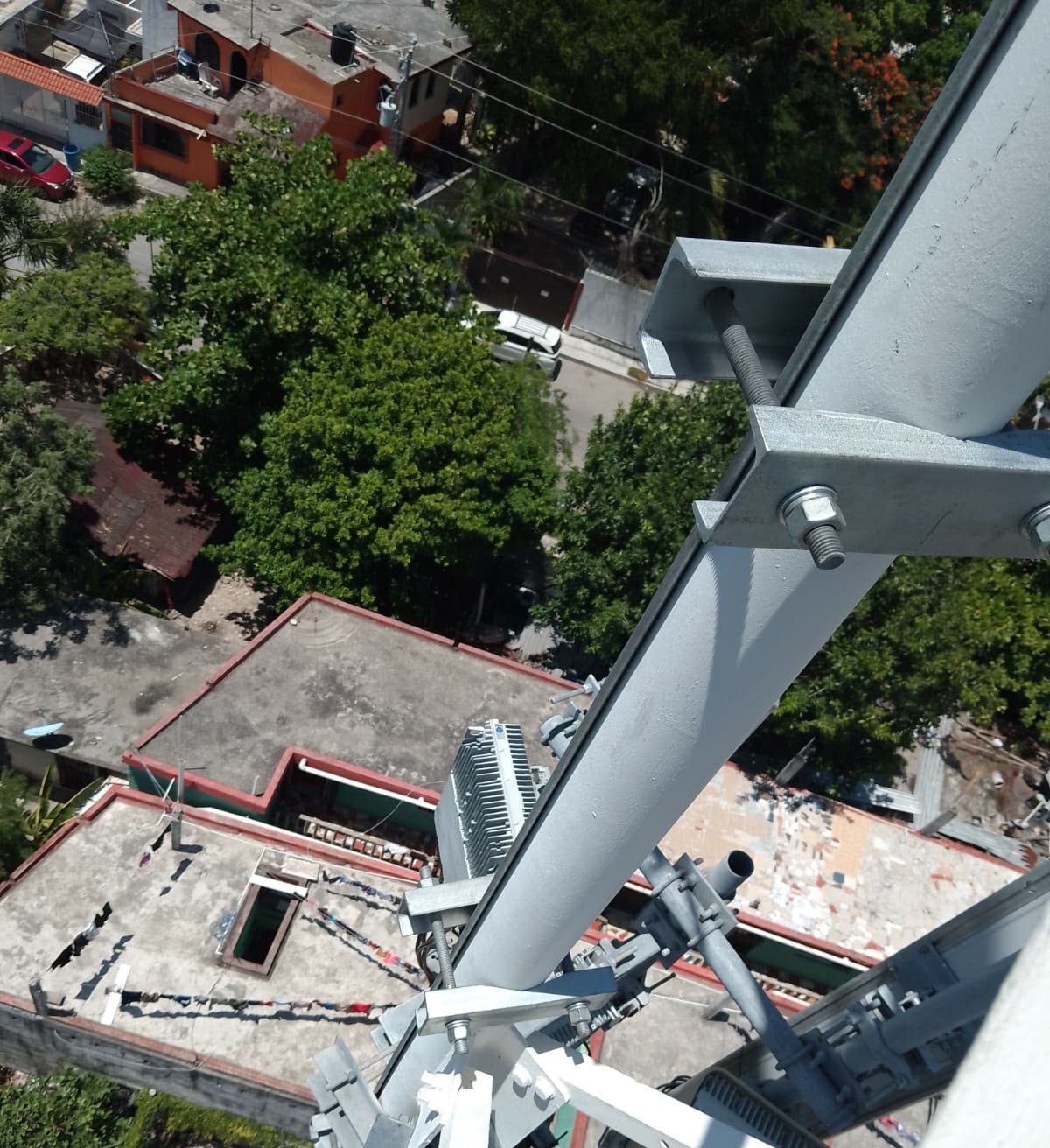 Perfil galvanizado del refuerzo atornillado en altura sobre la celosía de la torre, con las azoteas del barrio al fondo